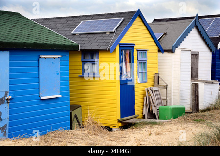 Strandhütten mit Sonnenkollektoren an Hengistbury Head in der Nähe von Bourenmouth in leuchtenden Farben. Stockfoto