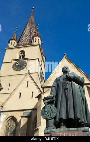 Statue des Bischofs Teutsch mit Uhrturm der lutherischen Kathedrale auf dem Hintergrund in Sibiu, Siebenbürgen, Rumänien Stockfoto