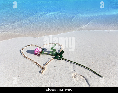 Am Strand zieht es Herz und die Rose liegt Stockfoto