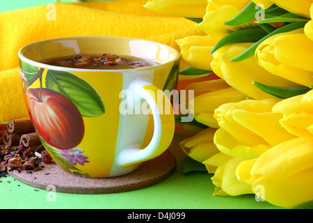 Teetassen und gelbe Tulpen auf grünem Hintergrund Stockfoto