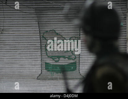 Srinagar, indisch verwalteten Kaschmir, Donnerstag, 14. März 2013. Ein indischer Polizist steht Wache als nächstes einen Closed Shop mit einem Kaschmir-Karte drauf gemalt, während eine Ausgangssperre in Srinagar im Sommer, die Hauptstadt des indischen Kaschmir, Indien verabreicht. Indische Behörden verhängte Ausgangssperre in Kaschmir, die Protestdemonstration zu vereiteln, nachdem sie einen 34 Jahre alten Mann am Mittwoch getötet. Foto von Sofi Suhail/Alamy) Stockfoto