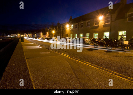 Autoscheinwerfer auf schmalen Küstenstraße. Ullapool, Highlands, Schottland Stockfoto