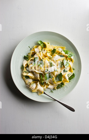 Ein Teller mit Pappardelle Pasta mit cremigem Ricotta, Baby-Spinat, frischen Kräutern und Pfeffer.