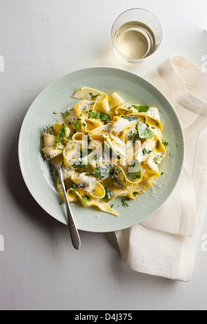 Ein Teller mit Pappardelle Pasta mit cremigem Ricotta, Baby-Spinat, frischen Kräutern und Pfeffer. Stockfoto