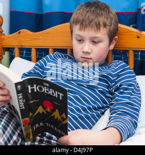 Ein neun Jahre alter Junge Buch der Hobbit in seinem Schlafzimmer Stockfoto
