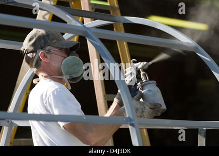 Bauarbeiter sprühen malt, während des Tragens Atemwege Sicherheitsausrüstung um sich von den Dämpfen in einer Fabrik zu schützen. Stockfoto