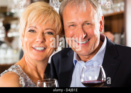 Älteres Paar im Restaurant stehen am Stab mit Glas Wein in der hand und Spaß Stockfoto