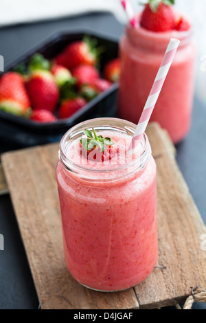 Nahaufnahme der Erdbeere Frucht-Smoothies und Tablett mit frischen Erdbeeren im Hintergrund Stockfoto