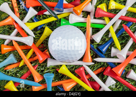 Ein Golfball unter einer Sammlung von farbigen hölzernen Tees. Stockfoto