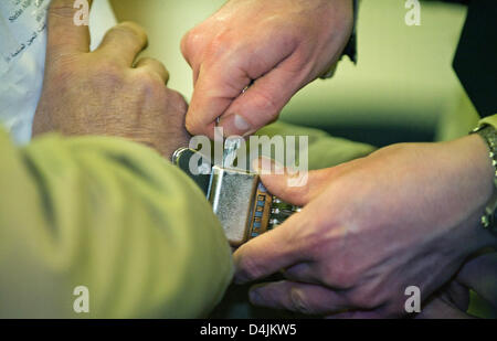 Ein Gerichtsvollzieher zieht die Handschellen des Beklagten Talid sagte O. aus dem Irak in den Gerichtssaal in regionalen Gericht Frankenthal, Deutschland, 16. Februar 2009. Der 40-Jahr-alten ehemaligen Polizei-Informant des Landes Rheinland-Pfalz? s Land Office of Criminal Investigation vorgeworfen wird, ermordet zu haben drei georgischen verwendet Autoverkäufer zusammen mit Somalis. Beide Männer Beschuldigten gegenseitig mit Stockfoto