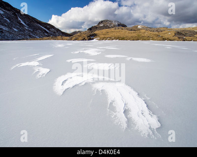 Wind trieb Schnee auf Beregnung Tarn an der Spitze des Borrowdale, gefroren, mit Blick auf große Ende, Lake District, Großbritannien. Stockfoto