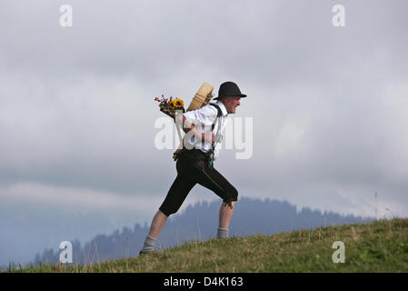 (Dpa-Datei) Eine Datei Bild vom 5. Oktober 2007 zeigt ein Senner tragen ein Rad von Käse in einem Rücken-Korb über die glatte Wiesen der Allgäu-Region in der Nähe von Immenstadt, Deutschland. Foto: Karl-Josef Hildenbrand Stockfoto