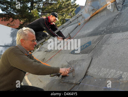 Kellerasseln Werner Uhlmann (L) und Udo Dabek Dach Fliesenleger Firma Hartenstein beginnen Reparationen des Daches der Kirche in Limbach-Oerfrohna, Deutschland, 31. März 2009. Eine 23-jährige Fahrer des Skoda verpasst eine Wende in der Nacht des 25. Januar 2009 und stürzte in die Kirche? s Dach. Seine einzigartige Stunt Sensation eine weltweite. Nach einem Gutachten hatte der Mann bei 13 beschleunigt. Stockfoto