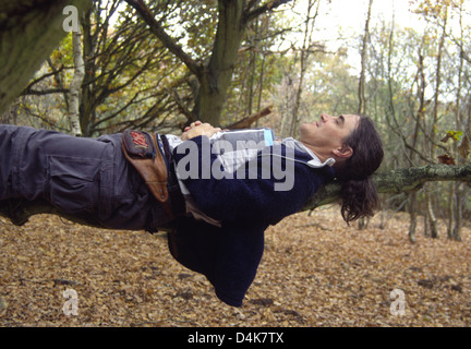 Mann liegt horizontal auf einem Ast erscheinen zu schweben in der Luft, UK Stockfoto