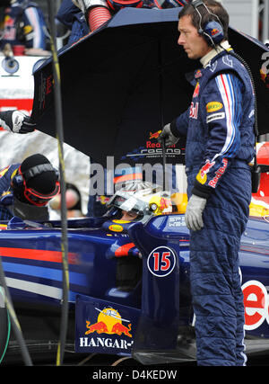 Deutsche Formel1-Fahrer Sebastian Vettel von Red Bull sitzt unter einem Regenschirm bei einem Boxenstopp während dem Qualifying für den Grand Prix von Deutschland am Nürburgring in Nuerburg, Deutschland, 11. Juli 2009. Die Formel 1 Grand Prix von Deutschland statt findet am Sonntag 12. Juli. Foto: PETER STEFFEN Stockfoto