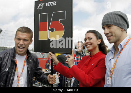 Deutscher Boxer Felix Sturm (R), WBA-Mittelgewichts-Weltmeister und deutschen Fußballspieler Lukas Podolski (L) posieren mit einem Raster-Mädchen vor Beginn des Grand Prix von Deutschland auf dem Nürburgring Rennstrecke in Nuerburg, Deutschland 12. Juli 2009. Foto: JENS Büttner Stockfoto