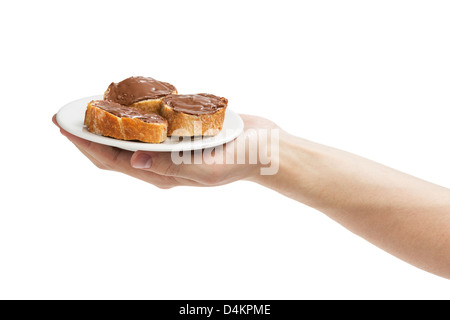 Baguette Scheiben mit Nuss-Schoko-Paste in die Hand des Mannes, isoliert auf weiss zu verbreiten Stockfoto
