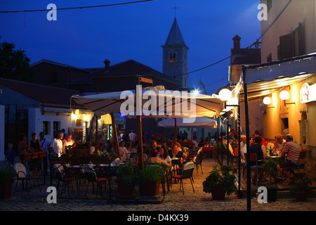 Menschen sind sitzend und mit Abendessen und Getränke außerhalb Restaurants auf dem Platz in Nin - kroatische beliebtes Urlaubsziel. Stockfoto
