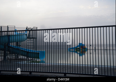 Öffentliches Freibad geschlossen für die Saison gesehen durch Zaun im Nebel Stockfoto