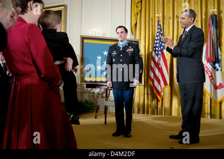 US Präsident Barack Obama ehemaliger Staff Sergeant Clinton Romesha vergibt die Medal Of Honor für auffallende Edelmut im Rahmen einer Feierstunde im East Room des weißen Hauses 11. Februar 2013 in Washington, DC. Auf der linken Seite hält Romeshas Frau Tammy ihre zwei-jährigen Sohn, Colin. Stockfoto