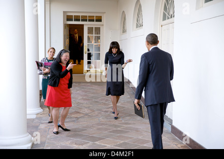 US-Präsident Barack Obama Uhren als First Lady Michelle Obama spielerisch ihn auf der Kolonnade des weißen Hauses 12. Februar 2013 in Washington, D.C. begrüßt. Tina Tchen, Chef des Stabes, der First Lady und persönlicher Adjutant Kristin Jones, links, begleiten Mrs Obama. Stockfoto