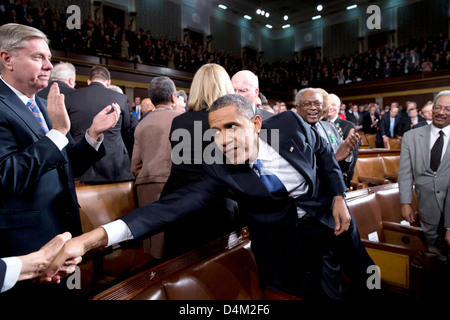 US-Präsident Barack Obama erreicht Hände mit einem Mitglied des Kongresses zu schütteln, wie er kommt, um den Zustand der Anschluß-Adresse auf dem US-Kapitol 12. Februar 2013 in Washington, DC zu liefern. Senator Lindsey Graham, begrüßt auf der linken Seite. Stockfoto