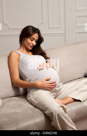 Schwangere Frau halten Bauch auf sofa Stockfoto