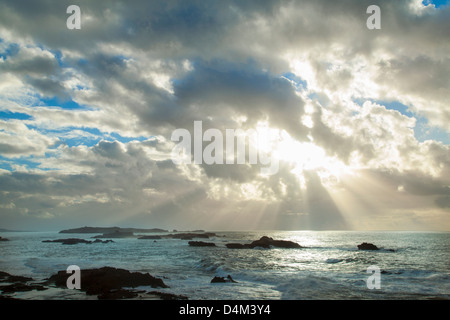 Sonne durch Wolken über Strand Stockfoto