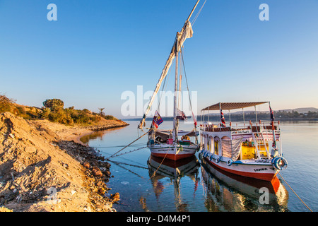 Felucca und Unterstützung Touristenboot vertäut am Ufer des Nils in der Nähe von Assuan bei Sonnenaufgang. Stockfoto