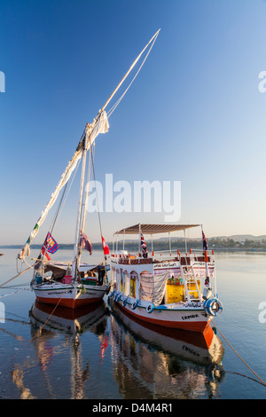 Felucca und Unterstützung Touristenboot vertäut am Ufer des Nils in der Nähe von Assuan bei Sonnenaufgang. Stockfoto