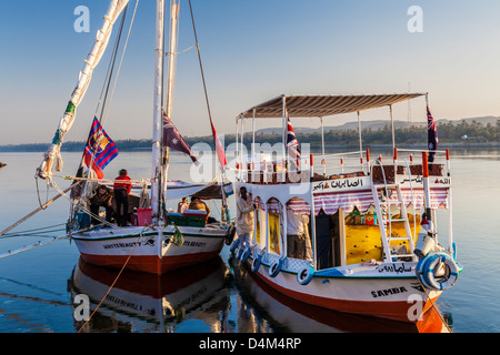 Felucca und Unterstützung Touristenboot vertäut am Ufer des Nils in der Nähe von Assuan bei Sonnenaufgang. Stockfoto