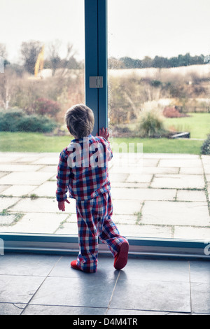 Junge im Pyjama aus Fenster Stockfoto