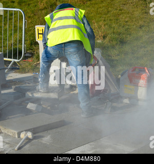 Arbeiter mit einem tragbaren Mauerwerk sah Maschine zum Schneiden von Pflaster Platte (Name aus Jacke entfernt) Stockfoto