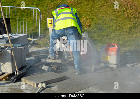 Arbeiter mit einem tragbaren Mauerwerk sah Maschine zum Schneiden Pflastersteine (Name aus Jacke entfernt) Stockfoto