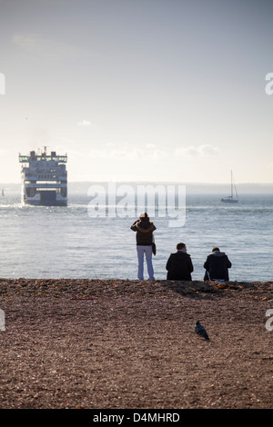 Menschen am Strand von Southsea in Portsmouth mit Blick zu einem Wightlink Auto Fähre in der Solent Überschrift nach Fishbourne, Isle Of Wight Stockfoto