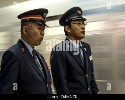 Zwei Eisenbahner, auf der Plattform als einen Zug der Ginza-Linie verlässt Shibuya Station. Stockfoto