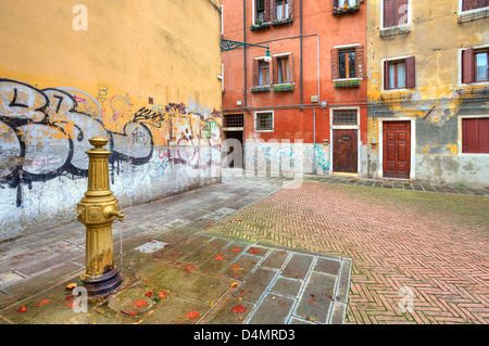 Wasserpumpe auf der kleinen Plaza unter alten typischen venezianischen bunte Häuser und Wände mit Graffiti in Venedig, Italien. Stockfoto