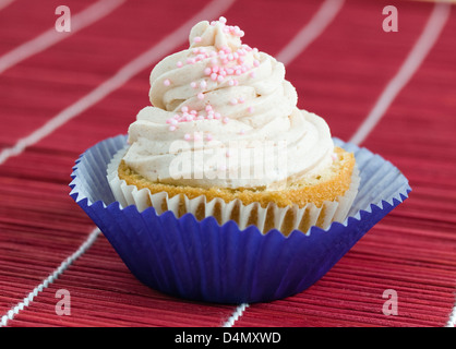 Ein Cupcake mit rosa Kugeln auf einem braunen Hintergrund Stockfoto
