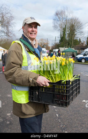 Thriplow Narzisse Wochenende, Cambridgeshire, Großbritannien. Samstag, 16. März 2013. Tim Holmes, Vorsitzender des Ausschusses Narzisse trägt ein Tablett mit eingemachten Narzissen. Die meisten der gepflanzten Narzissen haben noch aufgrund der kalten Frühling zu blühen. Wind und Regen nicht das jährliche Festival zu stoppen, wird von Tausenden von Besuchern besucht und geht morgen weiter. Die Veranstaltung wird organisiert von der Narzisse Wochenende Trust und sammelt Spenden für einen anderen guten Zweck jedes Jahr. Bildnachweis: Julian Eales / Alamy Live News Stockfoto