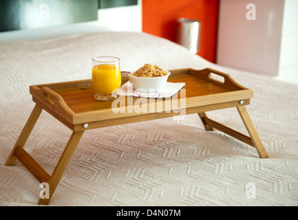 Frühstück mit Orangensaft auf einem Tablett im Bett Stockfoto