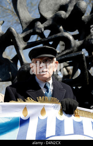 Holocaust-Überlebende Moshe Haelion halten eine Fahne der griechischen Juden Gemeinschaft und stand neben dem Holocaust-Mahnmal. Festschrift März zum 70. Jahrestag von der Abfahrt des ersten Zuges von Thessaloniki zu den Lagern der Nazis in Auschwitz. Start Point, das Holocaust-Mahnmal (Liberty) Eleftherias Square und Ziel der alte Bahnhof, wo der erste Zug mit der Juden von Thessaloniki abgereist. Thessaloniki, Griechenland. 16. März 2013. Zweitgrößte Stadt Griechenlands ist zum Gedenken an den 70. Jahrestag der ersten Deportation der Juden nach Auschwitz, mit einer Reihe von Stockfoto