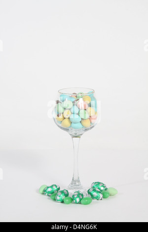 Glas Wein gefüllt mit Bonbons in verschiedenen Farben Stockfoto