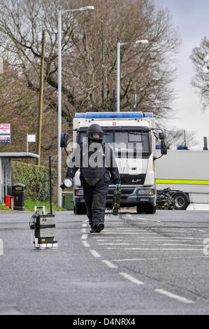 17.03.2013, Newtownabbey, Nordirland.  Offizier und ATO Fortschritte in Richtung einer verdächtigen Gerät. Das Objekt auf der Straße vor ihm zu sitzen ist eine elektronische Zähler messen (ECM) Anti-jamming Einheit, um zu verhindern, dass das Gerät per Fernbedienung gezündet wird. Stockfoto