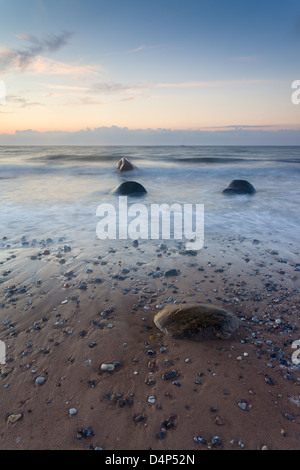 Wellen Waschen über Felsen am Strand bei Sonnenuntergang am Smidstrup Strand in Dänemark, August 2011 Stockfoto