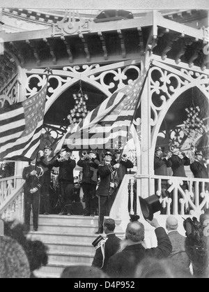 John Philip Sousa Band spielen am Musikpavillon während zwei Bandmitglieder auf Treppe stehen, winken amerikanische Flaggen - Paris Weltausstellung 1900 Stockfoto