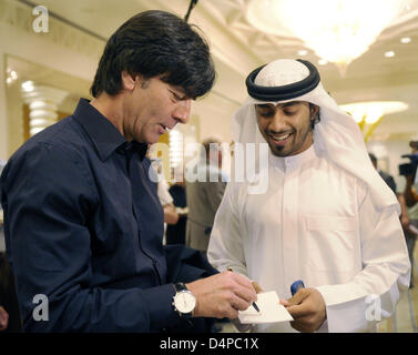 Joachim Löw (L), Cheftrainer der Deutschland? s Fußball Mannschaft unterzeichnet ein Autogramm für einen Fan in traditioneller Kleidung im Grand Hyatt Hotel in Dubai, Vereinigte Arabische Emirate (VAE), 1. Juni 2009. Die deutsche Nationalmannschaft ist auf eine Asientour, zwei Freundschaftsspiele zu spielen. Das erste Spiel gegen China endete mit einem 1: 1 zeichnen am 29 Mai, das zweite Spiel gegen die Vereinigten Arabischen Emirate findet am 02 Juni 200 Stockfoto
