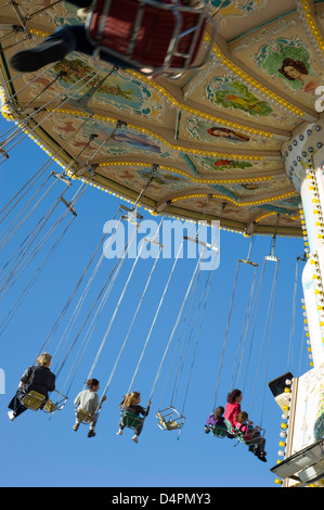 Eine gemischte Gruppe von Menschen in Höhe in auf einem Rummelplatz Stuhl fahren bei blauem Himmel im Hintergrund. Stockfoto