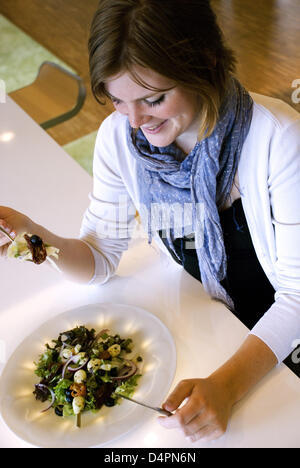 Dieses undatierte Bild zeigt eine junge Frau, die Essen aus einer Platte, die durch Technologie Student Lissa Kooijman von Eindhoven University of Technology entwickelt wurde. Die? EetMeet?-Platte hilft Benutzern, indem man sie länger kauen weniger zu essen. Sobald eine Gabel voll ist, Leuchten mehrere Lampen in den Rand der Platte. Der Benutzer soll nun das Essen kauen, bis die Lampen schalten sich wieder aus. Stockfoto