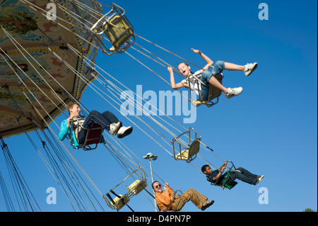 Eine gemischte Gruppe von Menschen in Höhe in auf einem Rummelplatz Stuhl fahren bei blauem Himmel im Hintergrund. Stockfoto