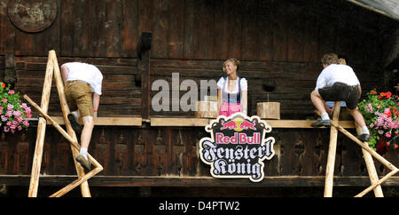 Zwei männliche Teilnehmer in der inoffiziellen? Fensterl? Meisterschaften (Red Bull Fensterl König) klettern Balkon die? Polz? Nkasparhaus?, wo Miss-Dirndl Veronika Wilbert in Garmisch-Partenkirchen, Deutschland, 22. August 2009 erwartet. Teilnehmer müssen ein Holzstapel, eine Leiter zu klettern und dann einen Nagel in eine Wand vor die schöne Dame küssen durfte. Die Wettbe Stockfoto